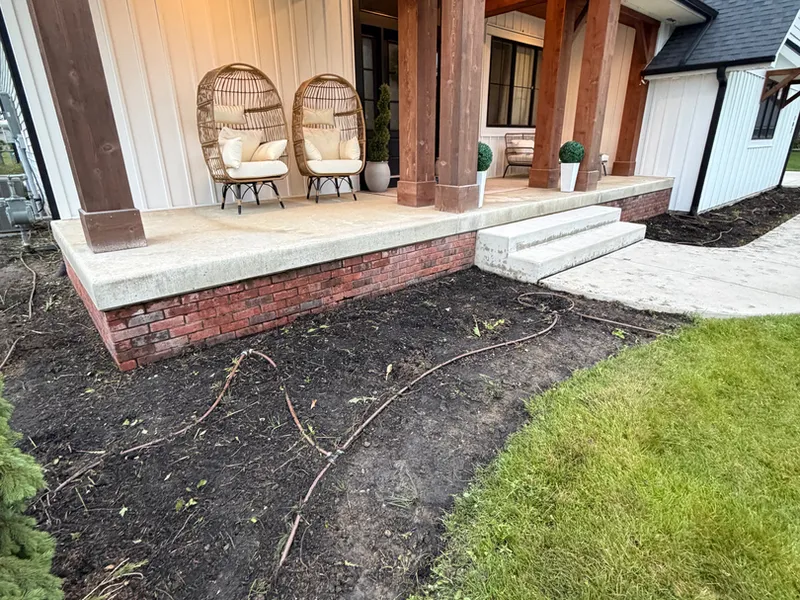 Black mulch bed and stone walkway leading to a covered front porch