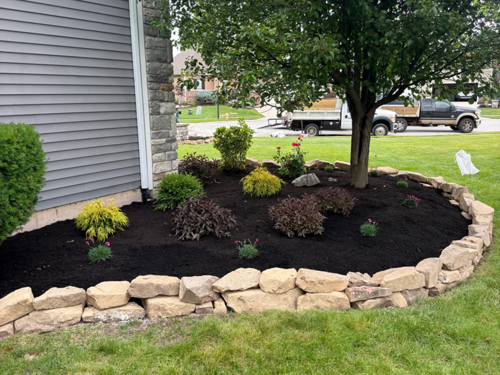 Boulder edged mulch bed with new plantings at a Fort Wayne area home