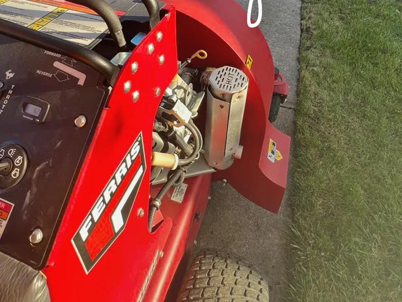 Red Ferris stand on mower working the lawn strip beside a residential sidewalk on an Autana route