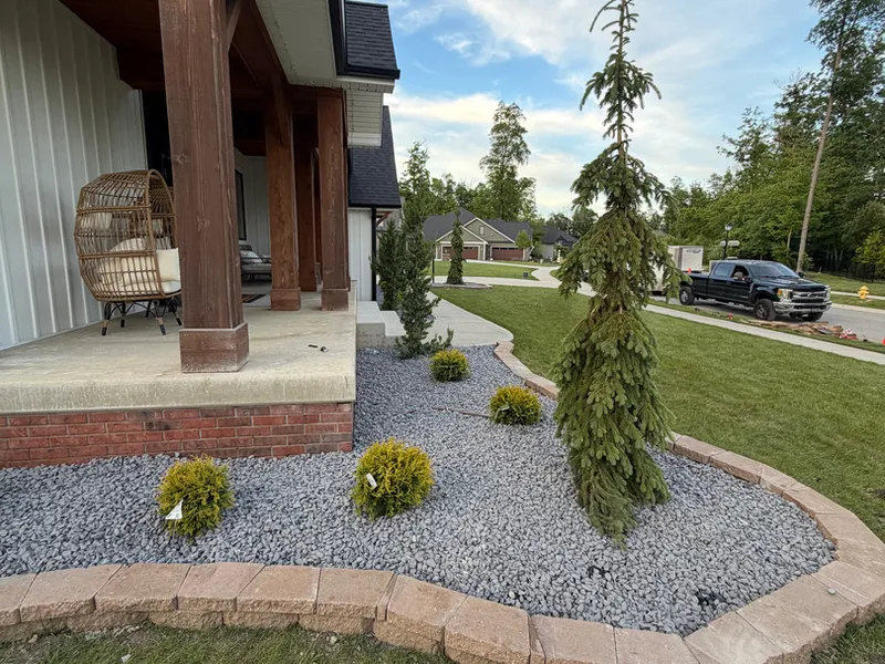 Gravel landscape bed with evergreens near a timber framed porch