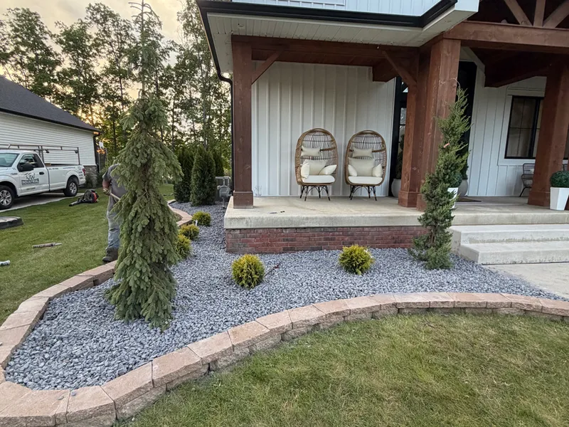 Gravel landscape bed with paver edging wrapping the front entry of a modern farmhouse