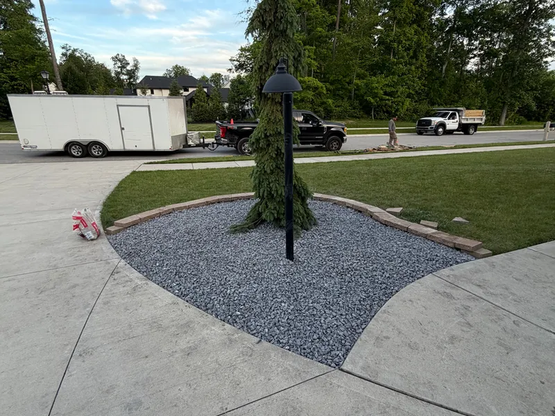 Gravel tree ring set beside a concrete driveway