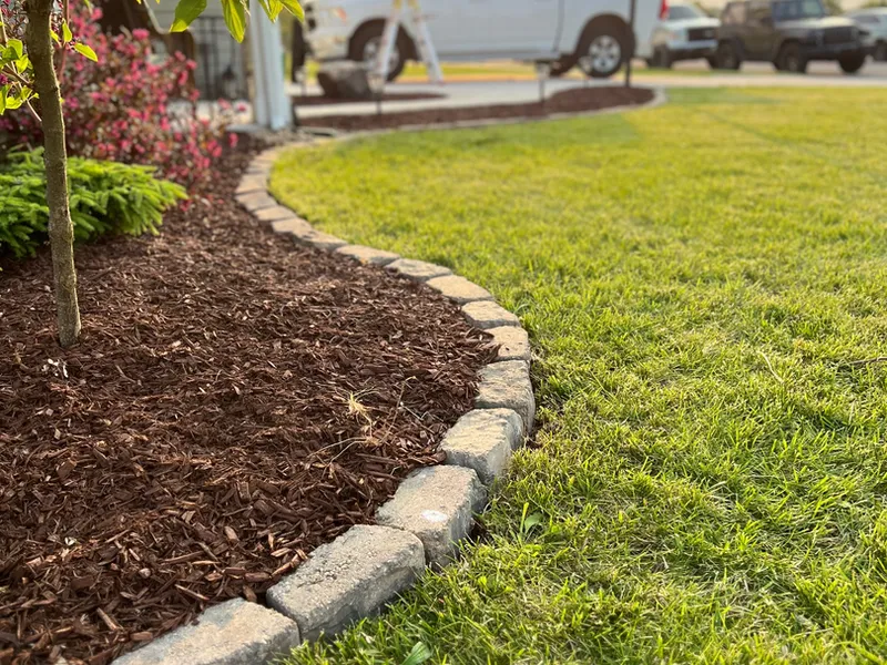 Mulch bed with stone edging photographed at golden hour