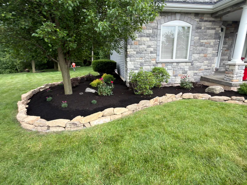 New landscape bed with fresh plantings and stone edging