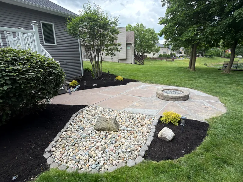 Finished paver patio with a fire pit and river rock border in a Fort Wayne area backyard