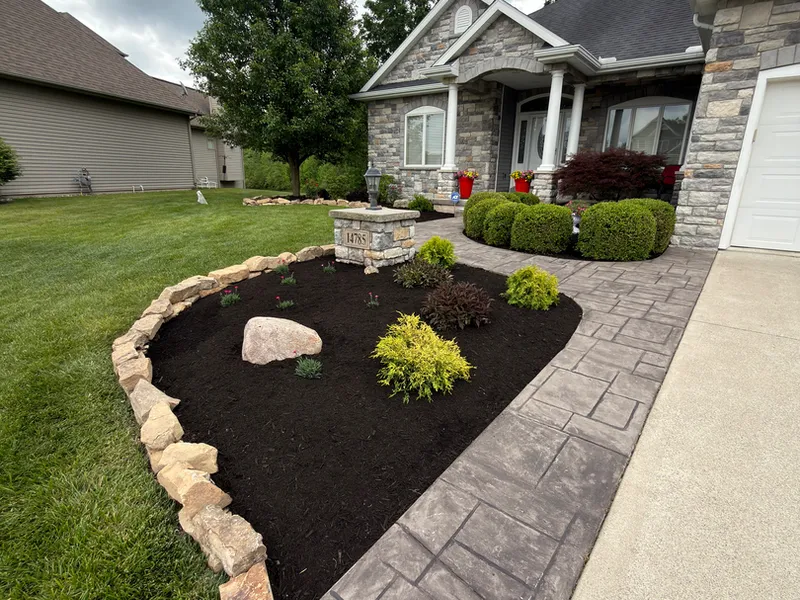 Stamped concrete walkway next to a boulder edged landscape bed at a suburban home